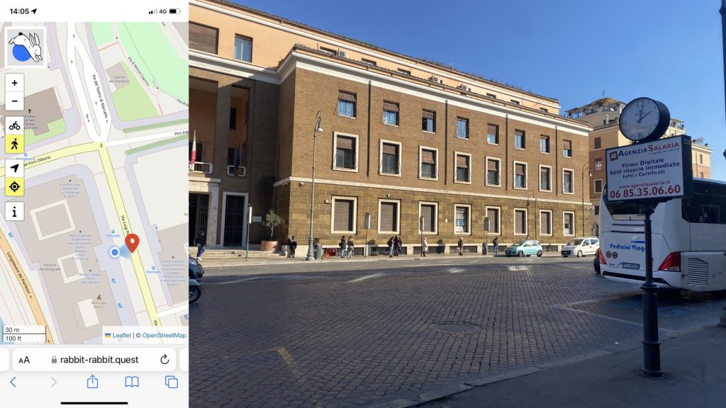 Composite image with my location on the left and on the right, the quest: an empty cobbled street, in shadow, with a municipal building opposite. There are three courses of windows on the front, mostly with their blinds up. In the foreground is a pole with a clock on it showing just after 2pm.