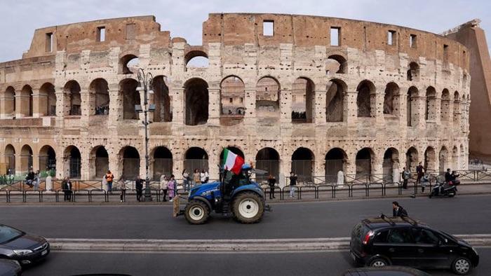 A single tractor, flying the Italian flag, passes the Colosseum in Rome